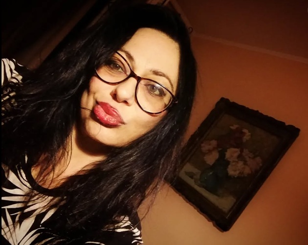 Ioana Popescu făcându-și un selfie într-o cameră întunecată, lângă un tablou cu o vază cu flori