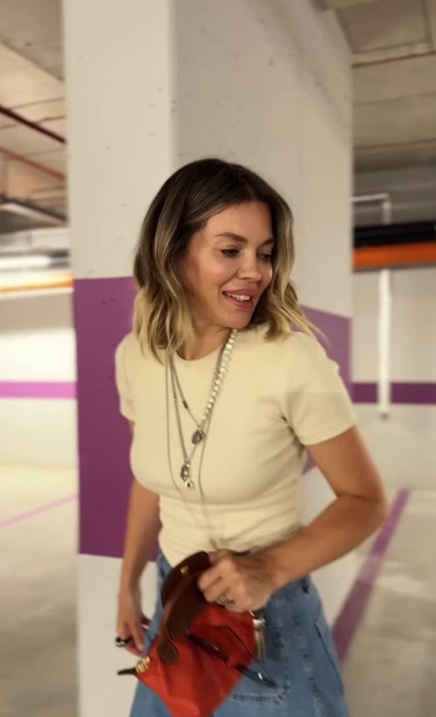 Gina Pistol în parcarea unui mall, uitându-se într-o parte, ținând în mână o poșetă roșie