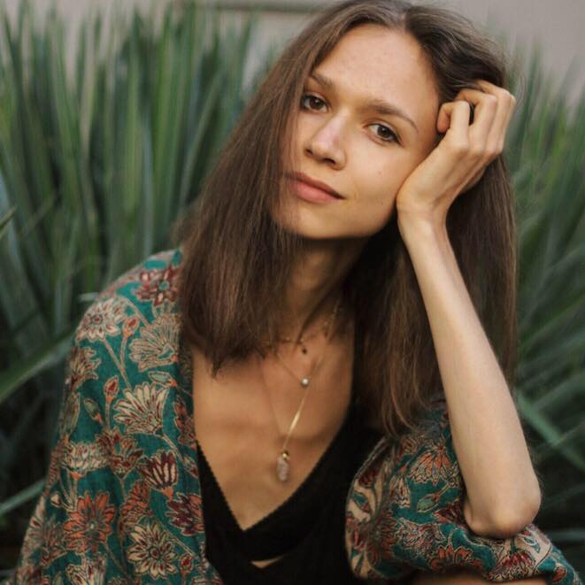 Karolina Krzyzak înainte să slăbească, zâmbitoare, sprijinindu-și capul cu mâna în timpul unei ședințe foto în natură