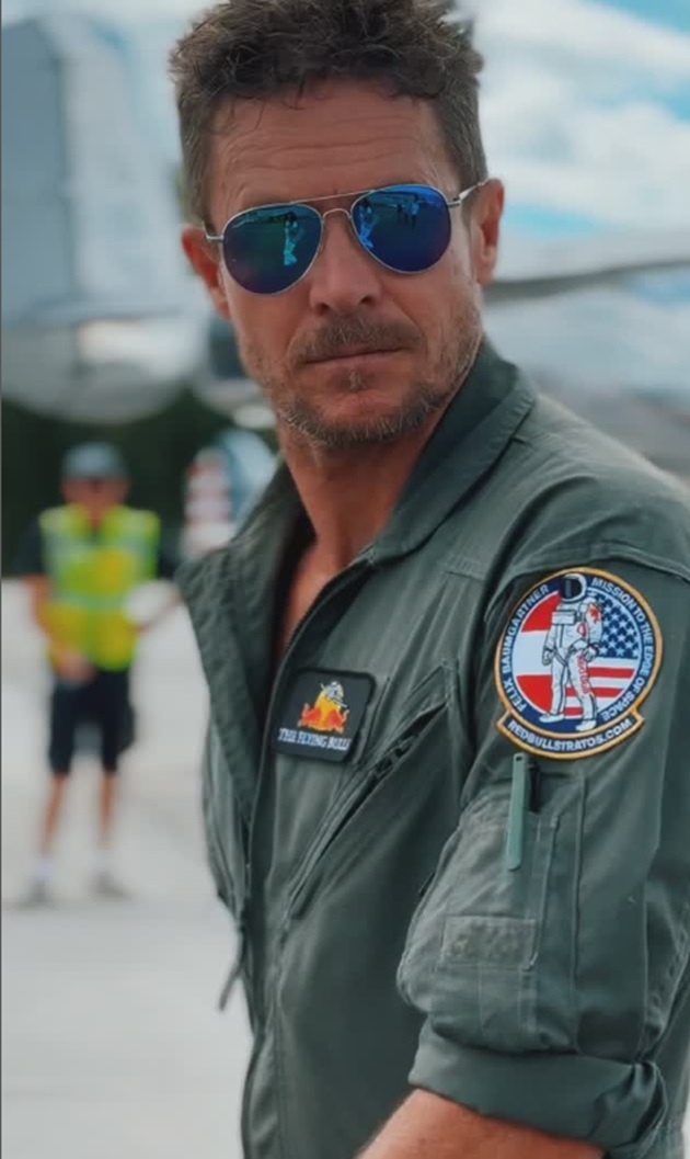 Felix Baumgartner în uniformă, cu ochelarii de soare la ochi, stând lângă un avion
