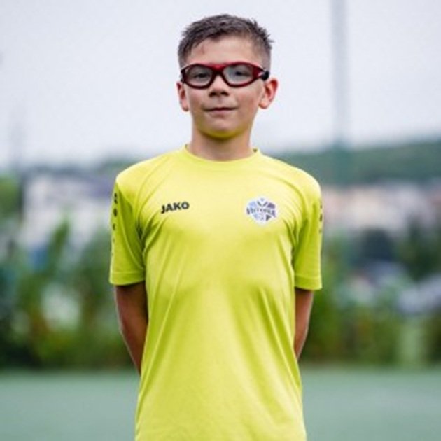 Eduard Balogh, băiatul de 12 ani rănit în accidentul din Cluj-Napoca, îmbrăcat în echipamentul de fotbal, stând la poză cu mâinile la spate, zâmbitor ș cu ochelarii de vedere la ochi