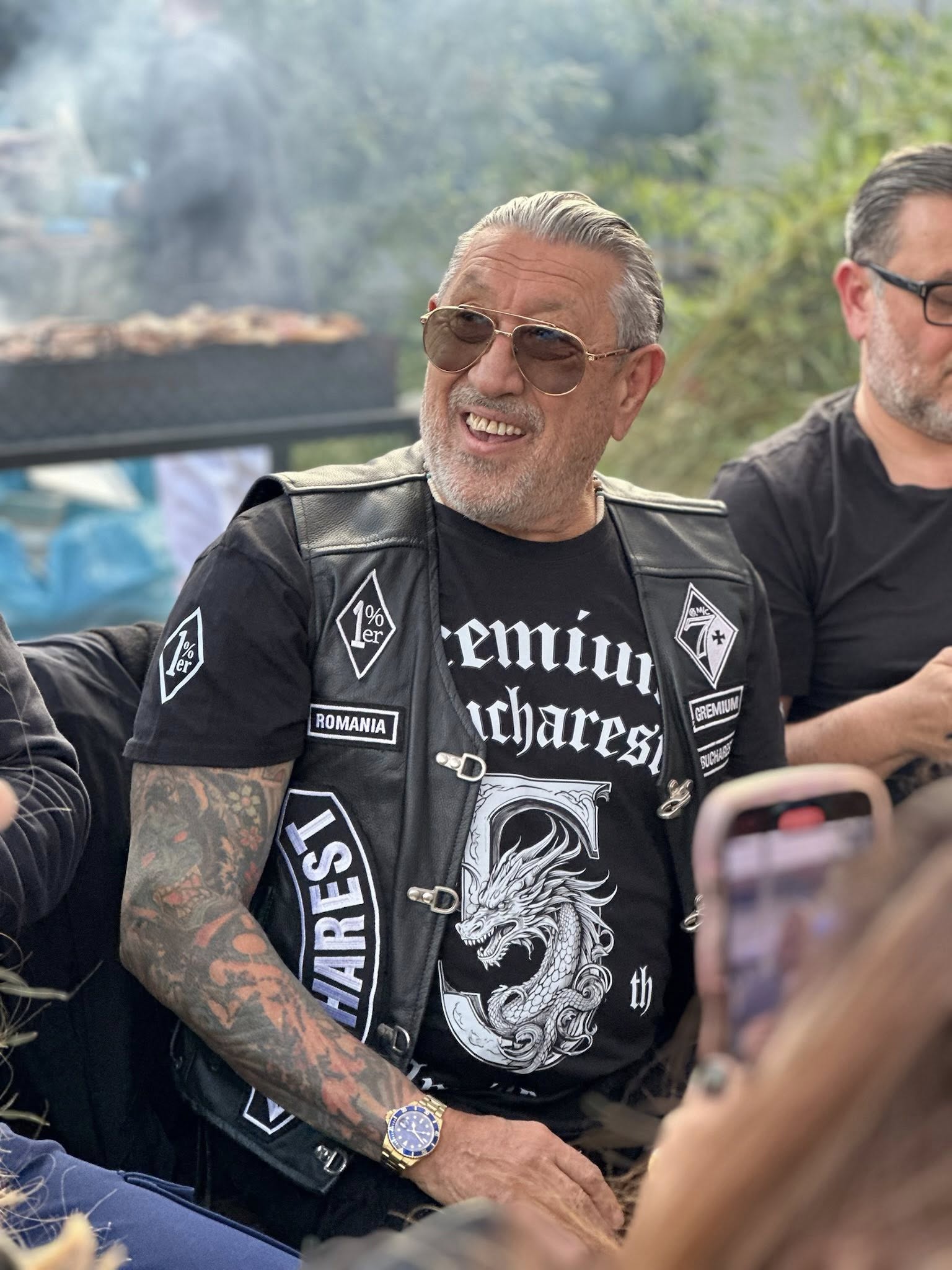 Serghei Mizil zâmbitor, purtând ochelari de soare, îmbrăcat într-un tricou negru peste care a pus o vestă de piele, tot neagră