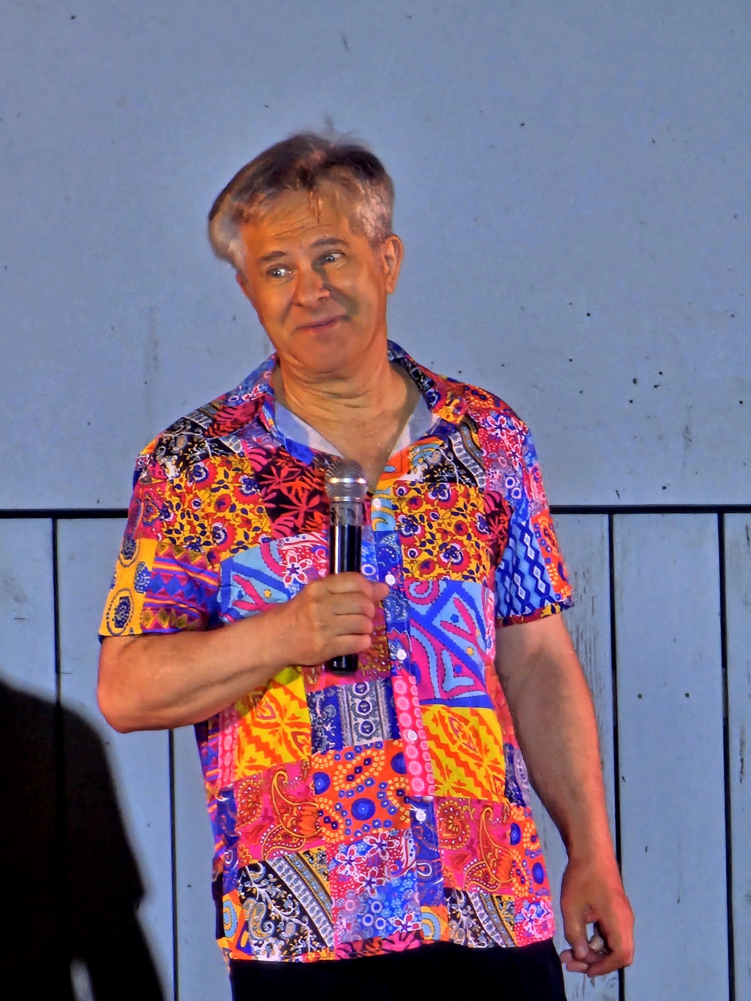 Doru Octavian Dumitru vorbind la microfon, în timpul unui spectacol, îmbrăcat în cămașă cu imprimeuri colorate