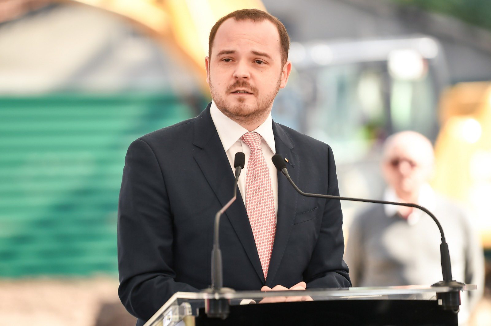 Alexandru Rogobete la un pupitru, cu microfonul în față, vorbind în fața unei audiențe.