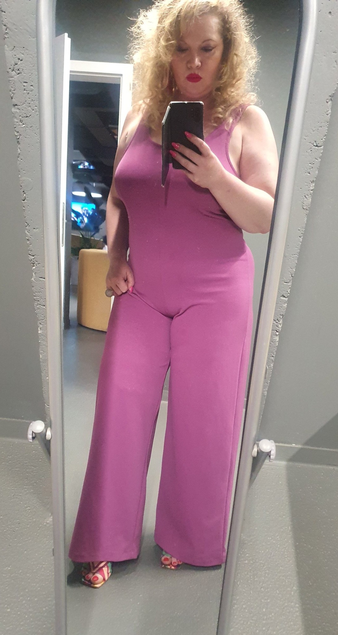 Oana Lis într-o salopetă roz, încălțată cu sandale cu toc, făcându-și un selfie în oglindă