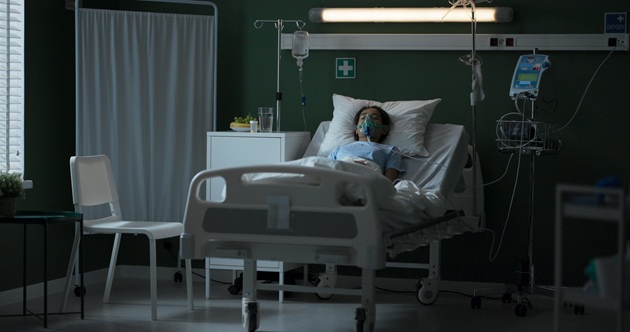 Tânără întinsă pe patul de spital, conectată la aparatul de oxigen