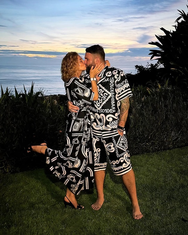 Soții Anna și Roman Novak sărutându-se pe malul unui lac, după apusul soarelui, îmbrăcați asortat, în seturi de cămașă și pantaloni, cu imprimeuri alb-negru