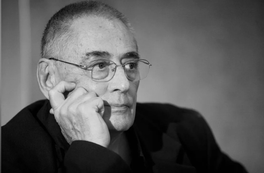 Imagine alb-negru cu Horia Moculescu gânditor, sprijinindu-și capul cu mâna, îmbrăcat în negru, cu ochelarii de vedere la ochi