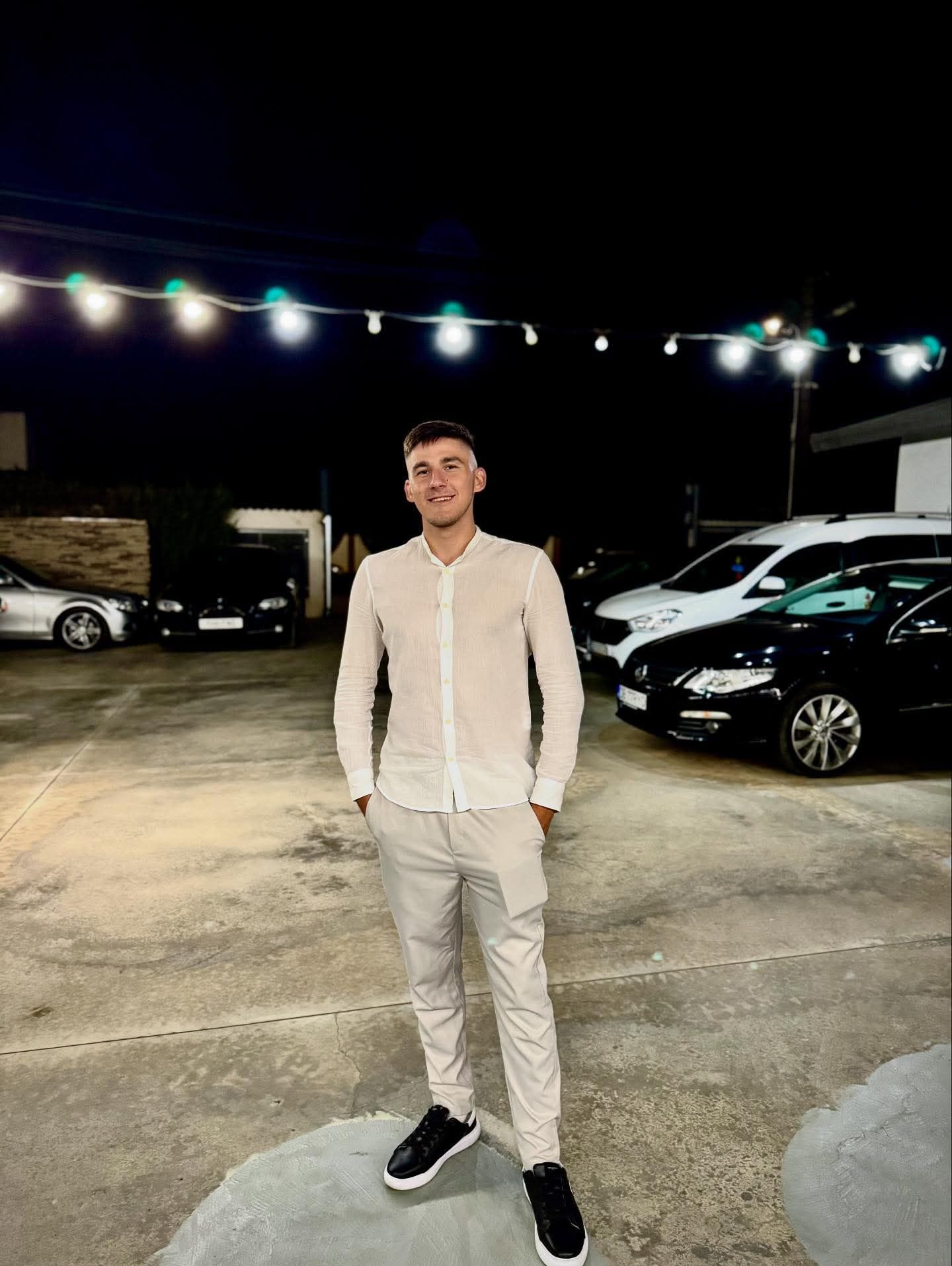 Laurențiu Marcu zâmbitor, îmbrăcat în alb, cu mâinile în buzunar