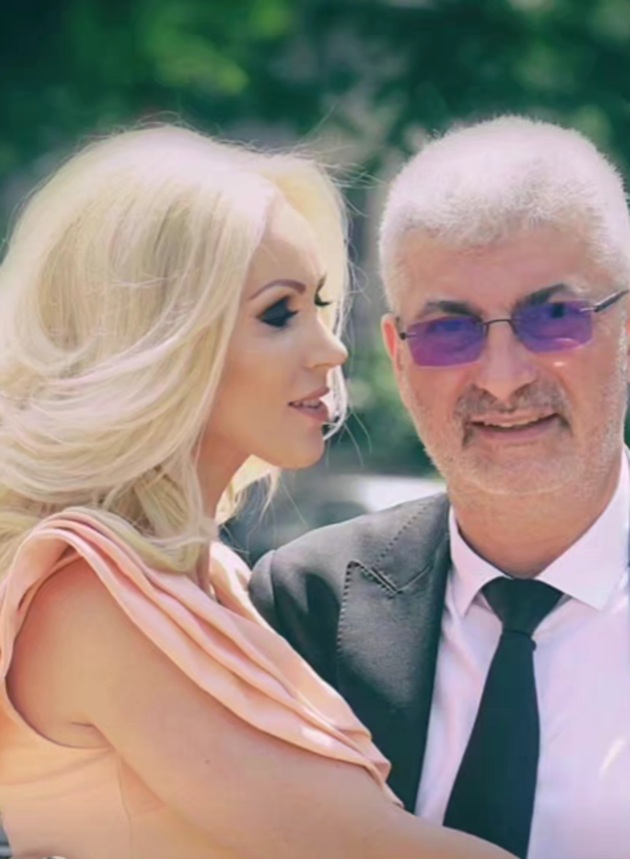 Mihaela Botezatu într-o rochie roz pal, îmbrățișându-l pe soțul ei, Silviu Prigoană, îmbrăcat într-un costum negru și o cămașă albă