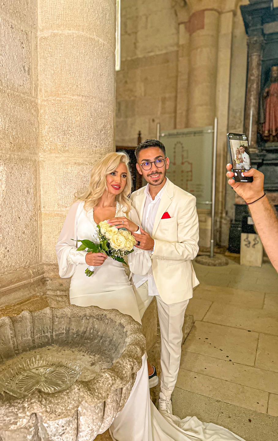 Armin Nicoară și soția sa, Claudia Puican, în ziua nunții lor, în timpul unei ședințe foto, arătând buchetul și inelul de logodnă