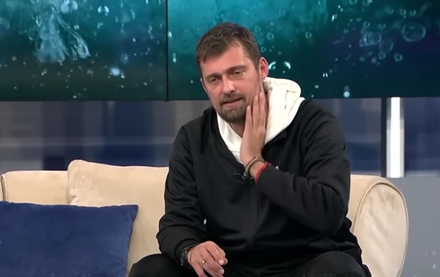 Gabi Tamaș, în direct la Antena Stars, îmbrăcat într-un trening negru și o bluză albă cu glugă, stând pe canapeaua emisiunii „Xtra Night Show”