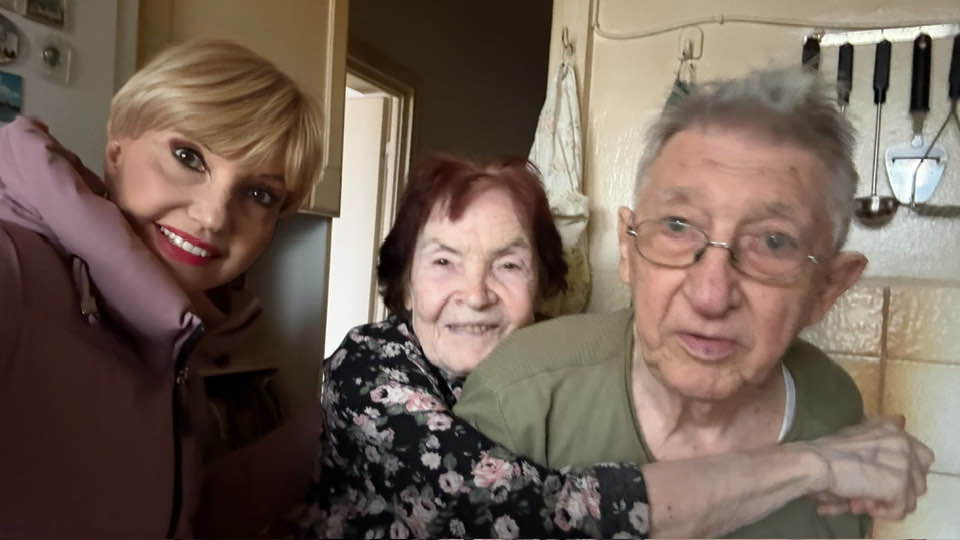 Marina Almășan zâmbitoare, alături de părinții ei, stând toți în bucătăria casei părintești din Floreasca