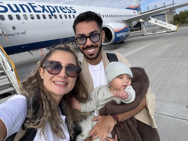 Claudia Puican și Armin Nicoară, pe pistă, în aeroport, pregătiți pentru o decolare, alături de fiul lor bebeluș, pe care saxofonistul îl ține în brațe în timp ce soția lui face o fotografie de familie