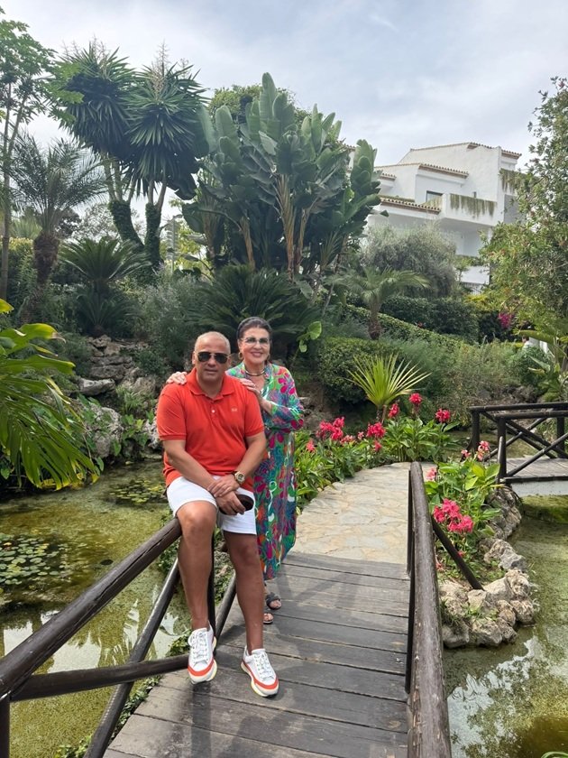 Irina Loghin și fiul ei Ciprian Cernea în timpul unei vacanțe în Marbella, stând pe un pod dintr-un parc cu multe plante