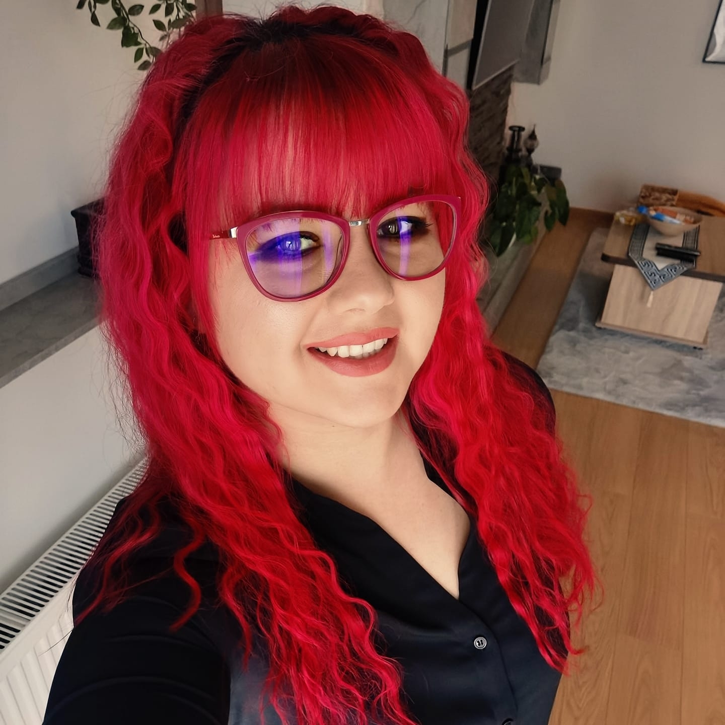 Elena Petrina zâmbitoare, cu părul roșcat și ochelari de vedere cu rame negre, îmbrăcată în negru, făcându-și un selfie