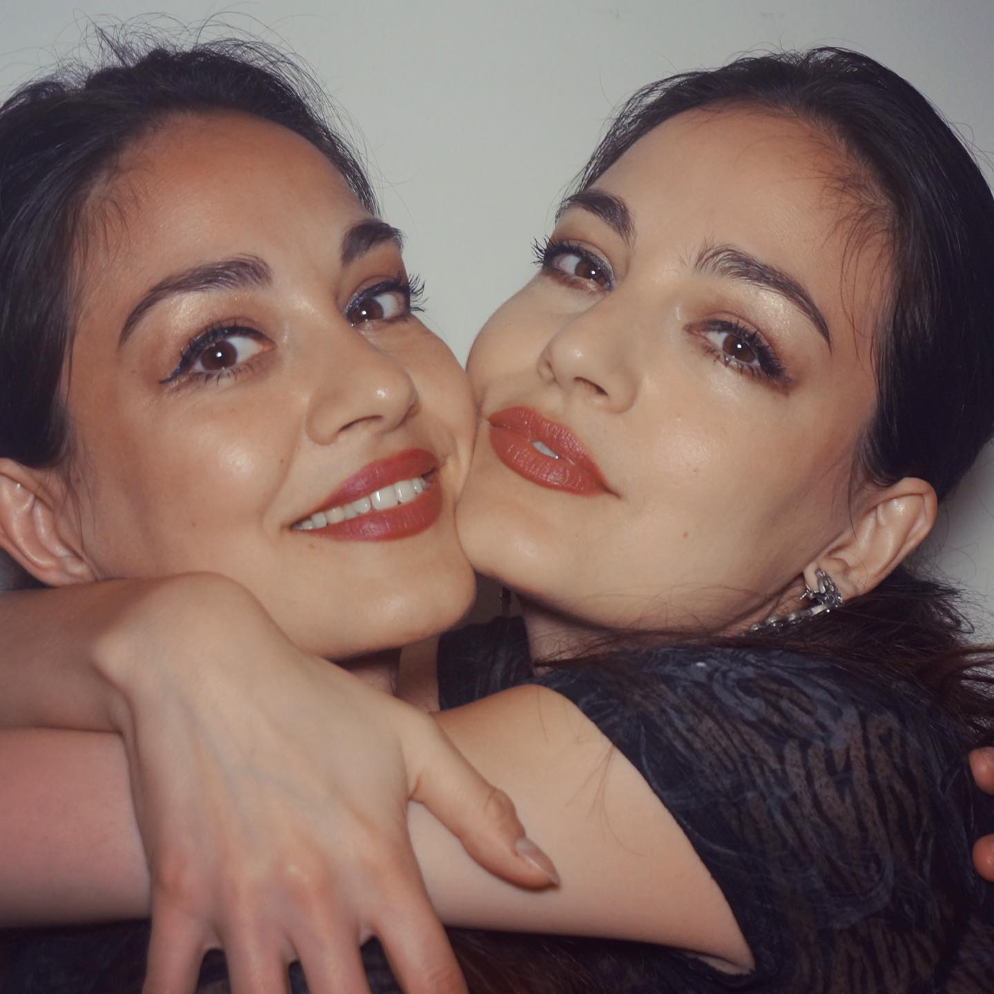 Gemenele Modorcea îmbrățișându-se strâns, în timp ce erau machiate și coafate identic, cu părul prins într-o coadă joasă la spate