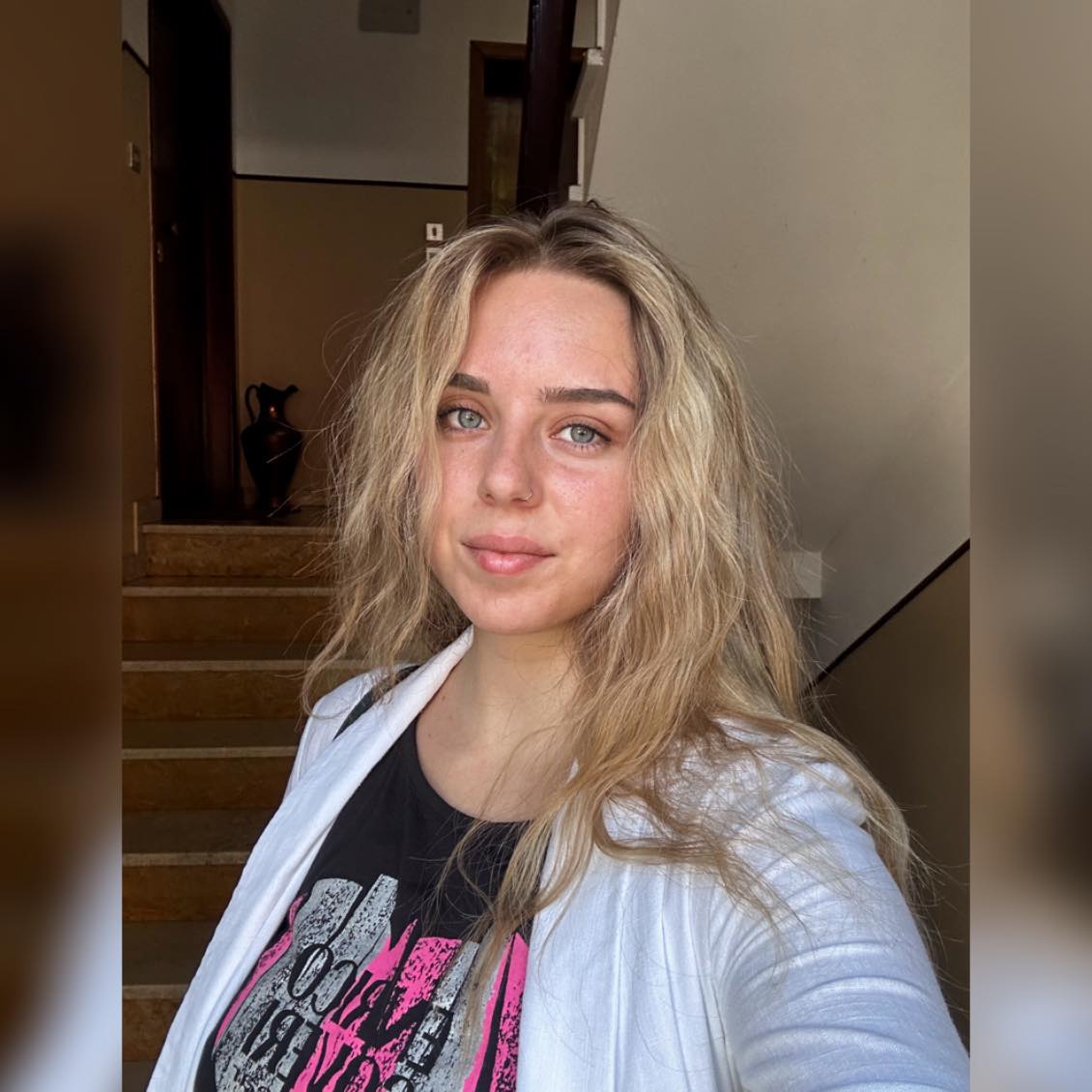 Georgiana Buloi în tricou negru, cu cămașă albă pe deasupra, cu părul ușor ondulat și fără machiaj pe față