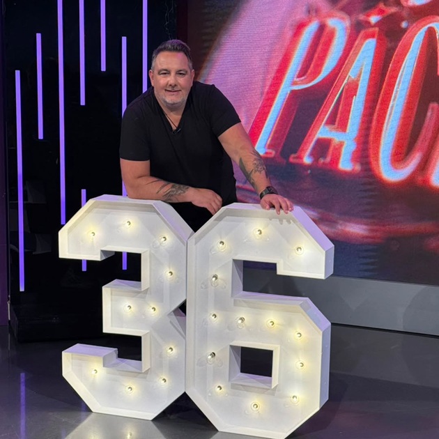 Dj-ul Silviu Andrei sprijinindu-se de două litere luminoase de mari dimensiuni, în platoul emisiunii „Un show păcătos” de la Antena Stars.