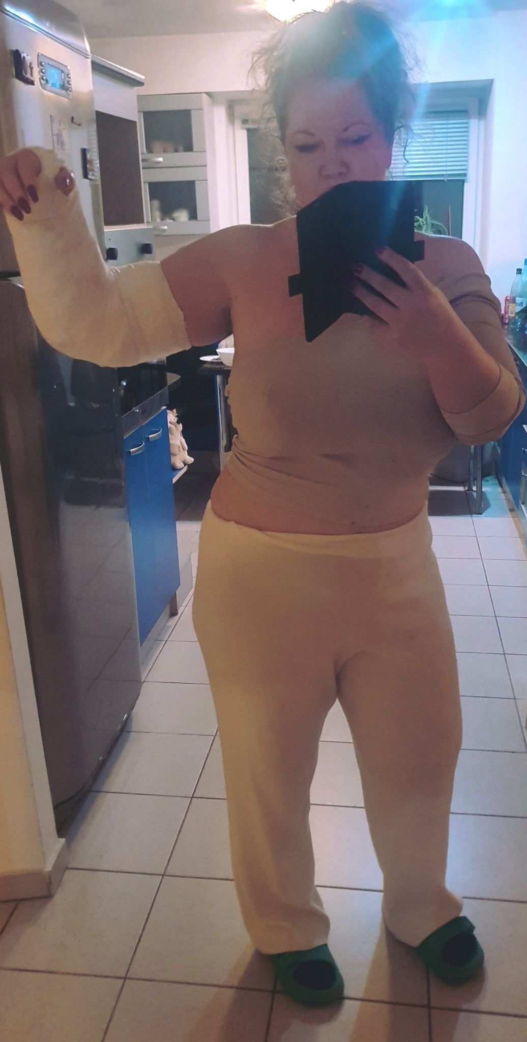 Oana Lis făcându-și un selfie în oglindă, cu mâna în ghips, cu părul ciufulit, îmbrăcată în haine de casă