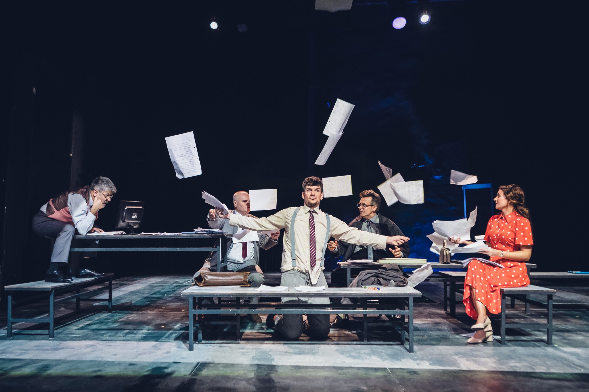 Tudor Chirilă pe scenă, aruncând un teanc de foi, fiind înconjurat de colegii actori, în timpul unei piese de teatru