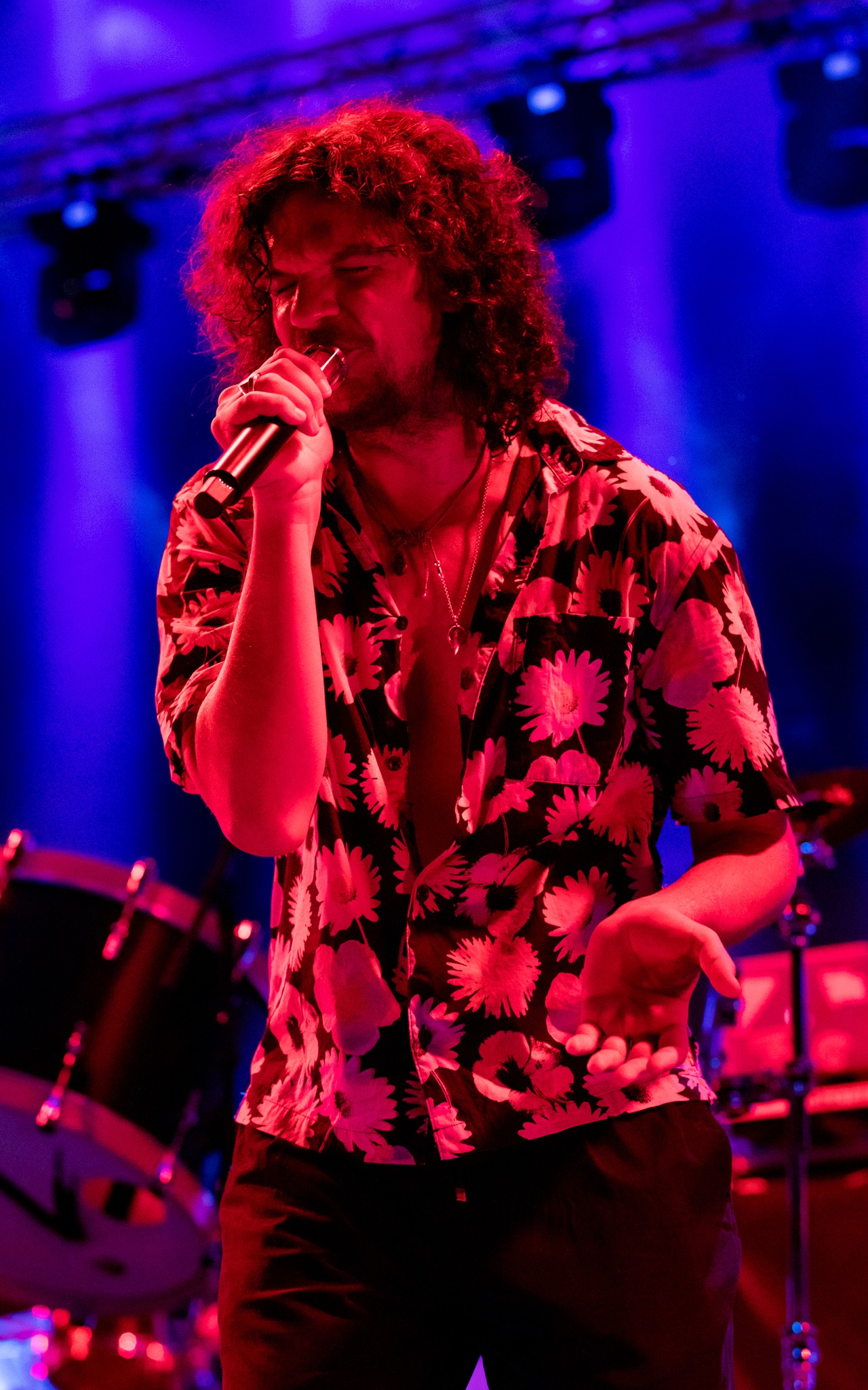 Tudor Chirilă cu părul lung, c&acirc;rlionțat, c&acirc;nt&acirc;nd pe scenă, &icirc;n fața publicului său, &icirc;n luminile colorate ale reflectoarelor