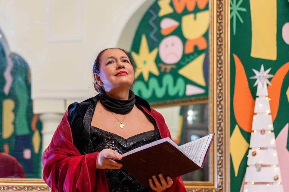 Soprana Anda-Louise Bogza &icirc;n timpul unui concert de colinde, &icirc;n anul 2022, &icirc;mbrăcată &icirc;ntr-o rochie neagră, cu un șan vișiniu pe umeri