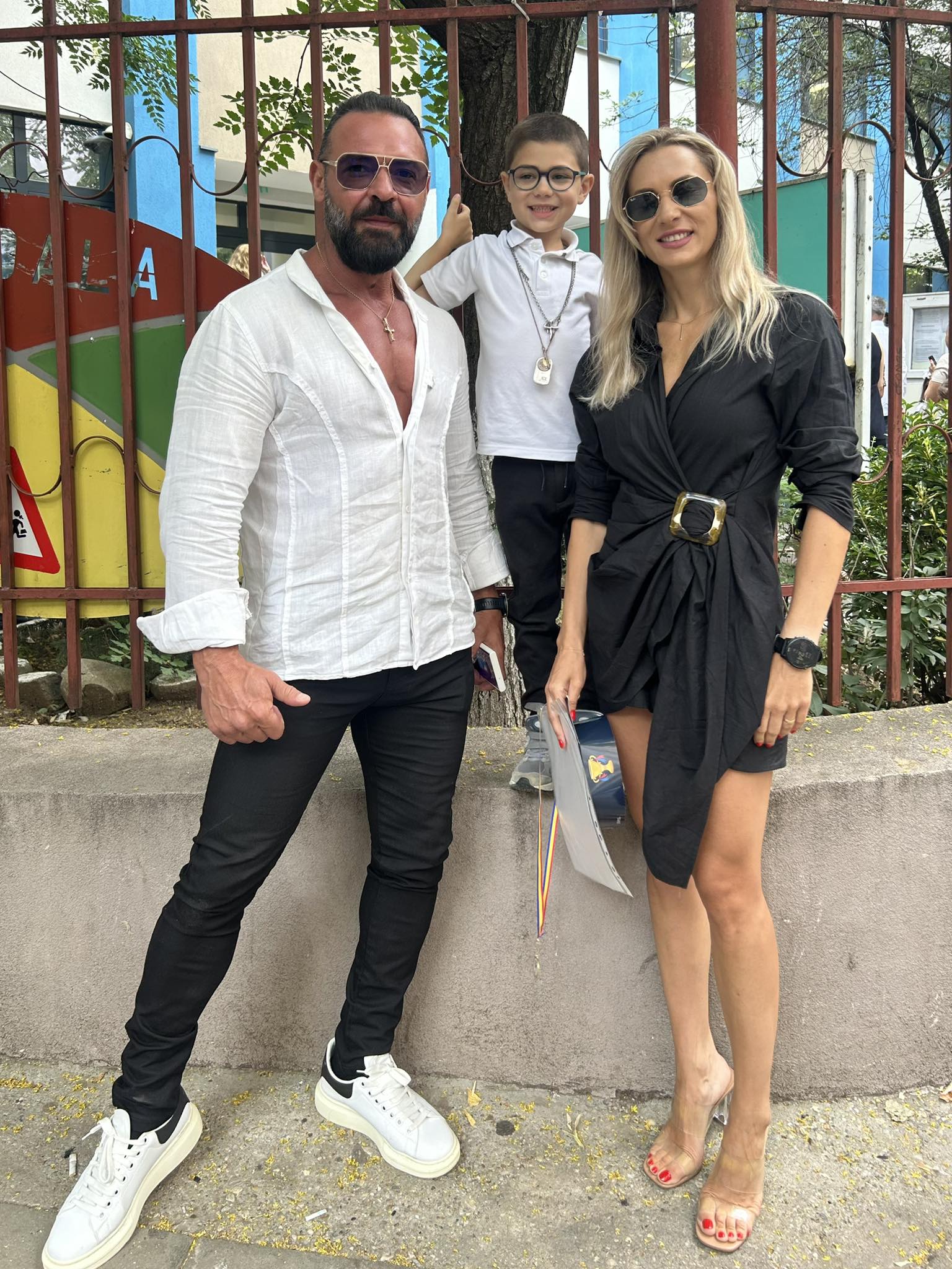 Cornel Păsat și Bianca alături de fiul lor, Dryas, l&acirc;ngă gardul grădiniței, la festivitatea de final de an școlar