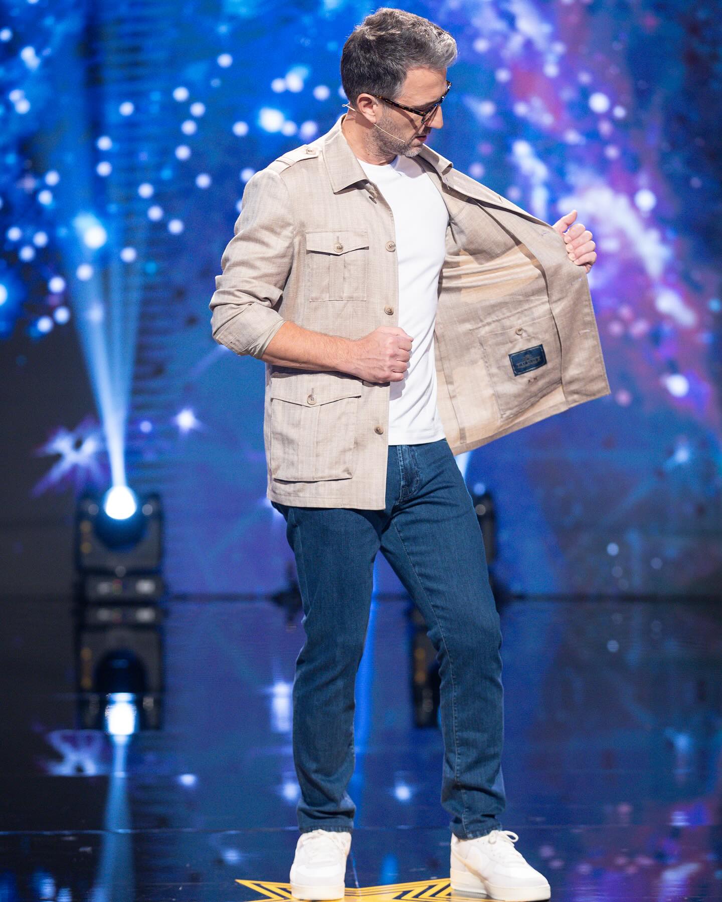 Andi Moisescu pe scena &bdquo;Rom&acirc;nii au talent&rdquo;, uit&acirc;ndu-se pe interiorul saciului său bej, la buzunarul interior