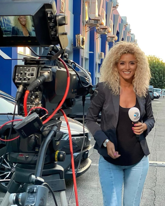 Nicoleta Drăguișin z&acirc;mbitoare, &icirc;n blugi, tricou negru și sacou gri, &icirc;naintea unei transmisiuni live pentru postul Kanal D, țin&acirc;nd microfonul &icirc;n m&acirc;nă și st&acirc;nd l&acirc;ngă cameră