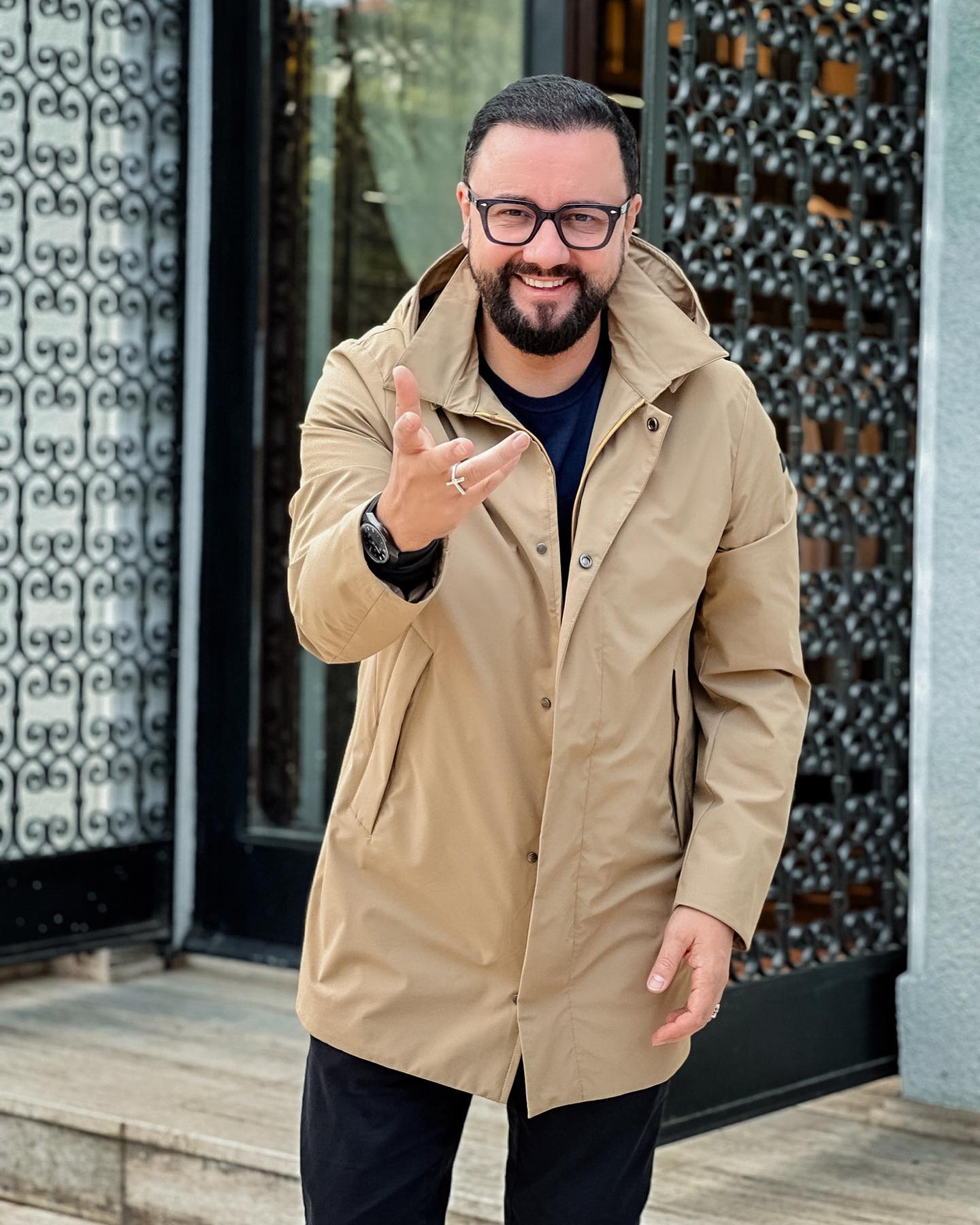 Cătălin Măruță z&acirc;mbitor, &icirc;n pantaloni negri și geacă bej, lungă