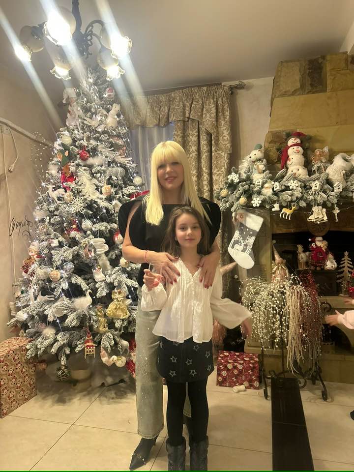 Elena Udrea &icirc;mbrățiș&acirc;ndu-și fiica l&acirc;ngă bradul de Crăciu
