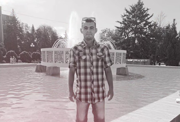 Imagine alb-negru cu Ruslan, fiul Iuliei&nbsp;Buga, din Republica Moldova, st&acirc;nd l&acirc;ngă o f&acirc;nt&acirc;nă arteziană, &icirc;mbrăcat &icirc;n blugi și &icirc;n cămașă cu carouri