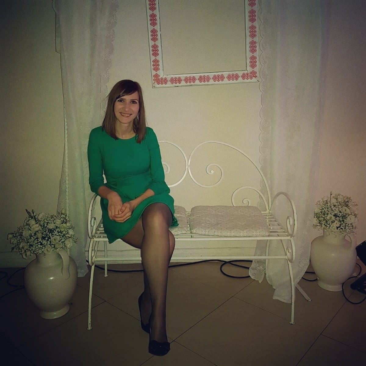 Laura, femeia care a murit după ce a fost internată la Spitalul Județean Constanța, z&acirc;mbitoare, &icirc;mbrăcată &icirc;ntr-o rochie verde, cu dresuri negre și pantofi negri, st&acirc;nd pe o bancă albă de metal