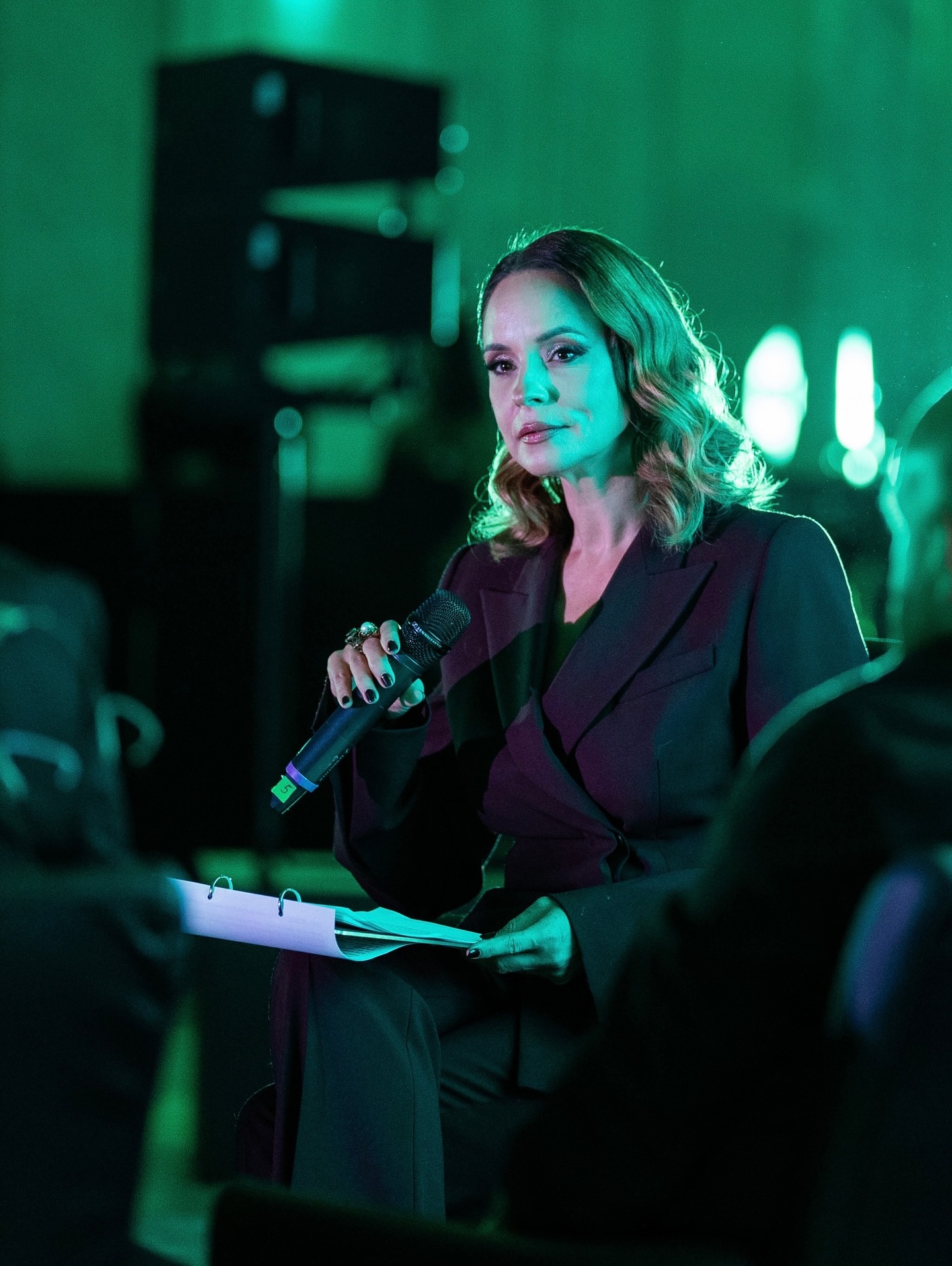 Andreea Marin la un eveniment, vorbind la microfon &icirc;n fața publicului, extrem de serioasă, &icirc;mbrăcată &icirc;ntr-un costum negru