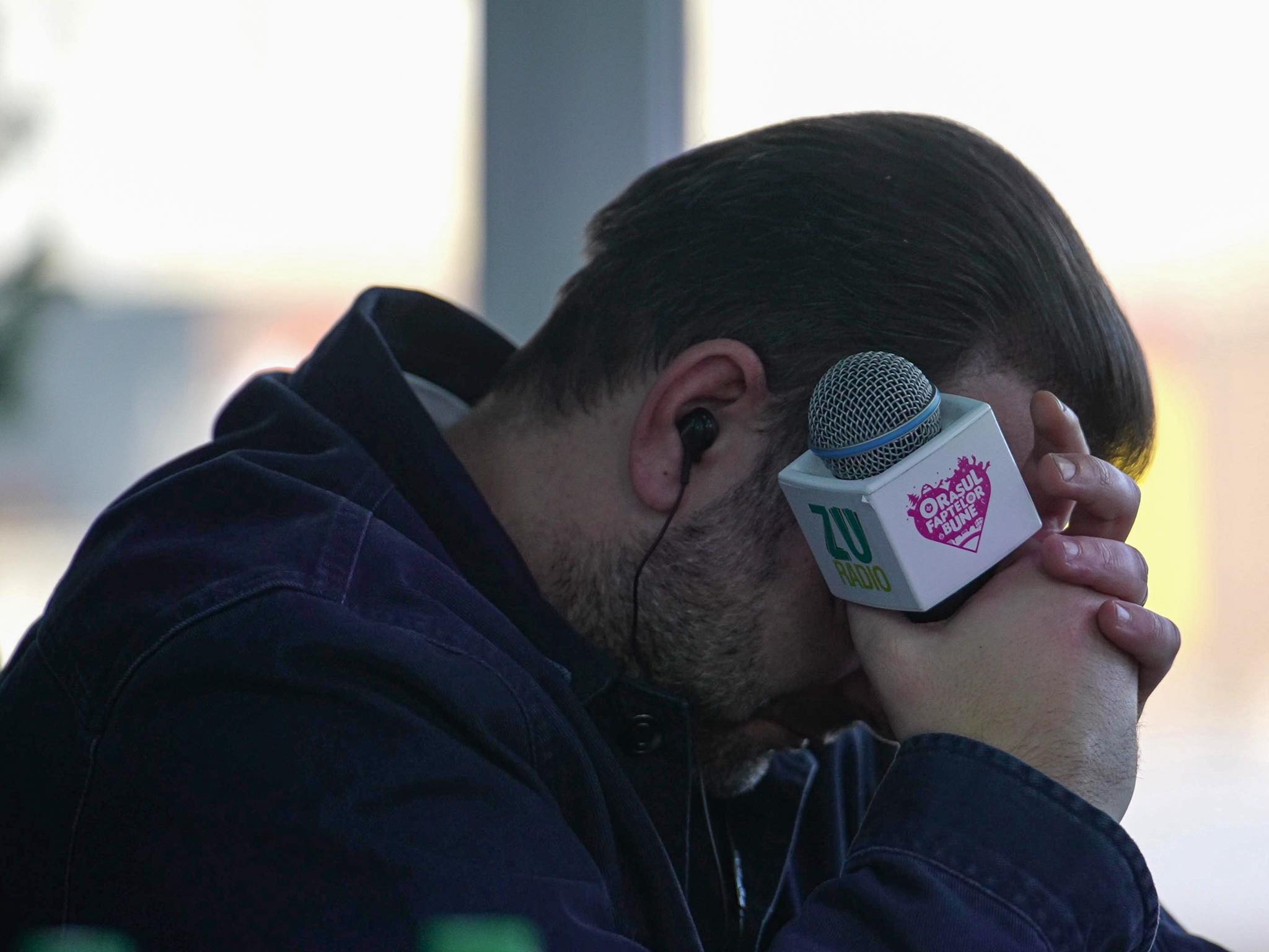 Mihai Morar pl&acirc;ng&acirc;nd la Orașul Faptelor Bune, &icirc;n timp ce &icirc;și acoperea fața cu m&acirc;inile &icirc;n care ținea un microfon inscripționat cu numele campaniei umanitare