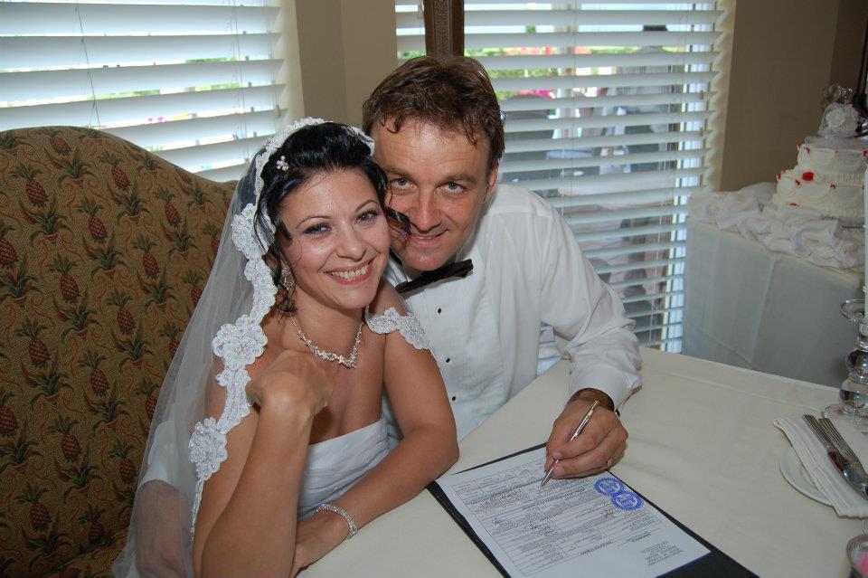 Elena C&acirc;rstea și soțul ei,&nbsp;Glenn&nbsp;Muttart, semn&acirc;nd actele de căsătorie, &icirc;n ziua nunții lor, z&acirc;mbitori și &icirc;mbrăcați &icirc;n mire și mireasă