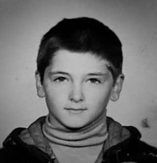 Imagine alb-negru cu Mircea Radu &icirc;n copilărie, &icirc;mbrăcat &icirc;ntr-un hanorac, privind serios &icirc;n obiectivul aparatului de fotografiat.