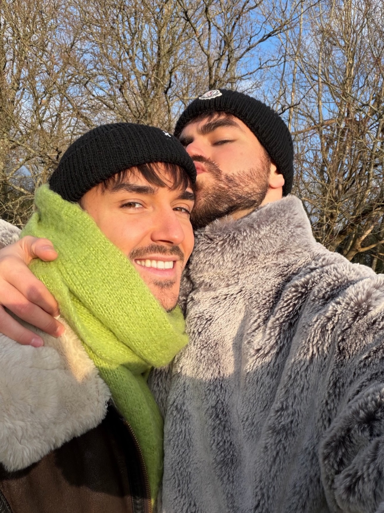 Alejandro Fernandez sărut&acirc;ndu-l pe cap pe iubitul său, Emil Rengle, &icirc;n timpul unei plimbări &icirc;n natură, iarna, &icirc;n timp ce purtau am&acirc;ndoi haine groase, căciuli și fulare