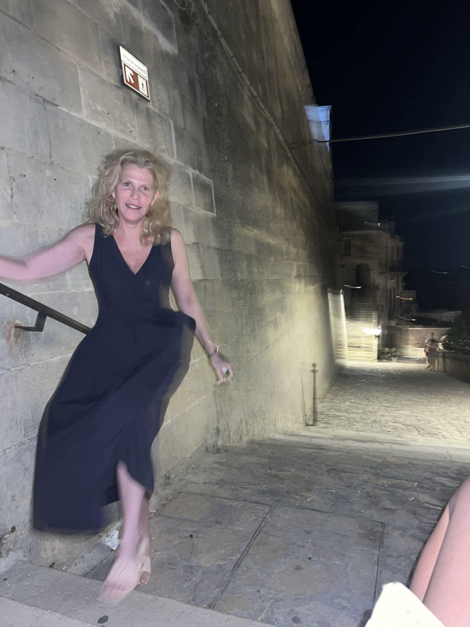 Dana Eden &icirc;n rochie neagră, la o plimbare de seară, pe treptele unei clădiri, țin&acirc;ndu-se de balustradă