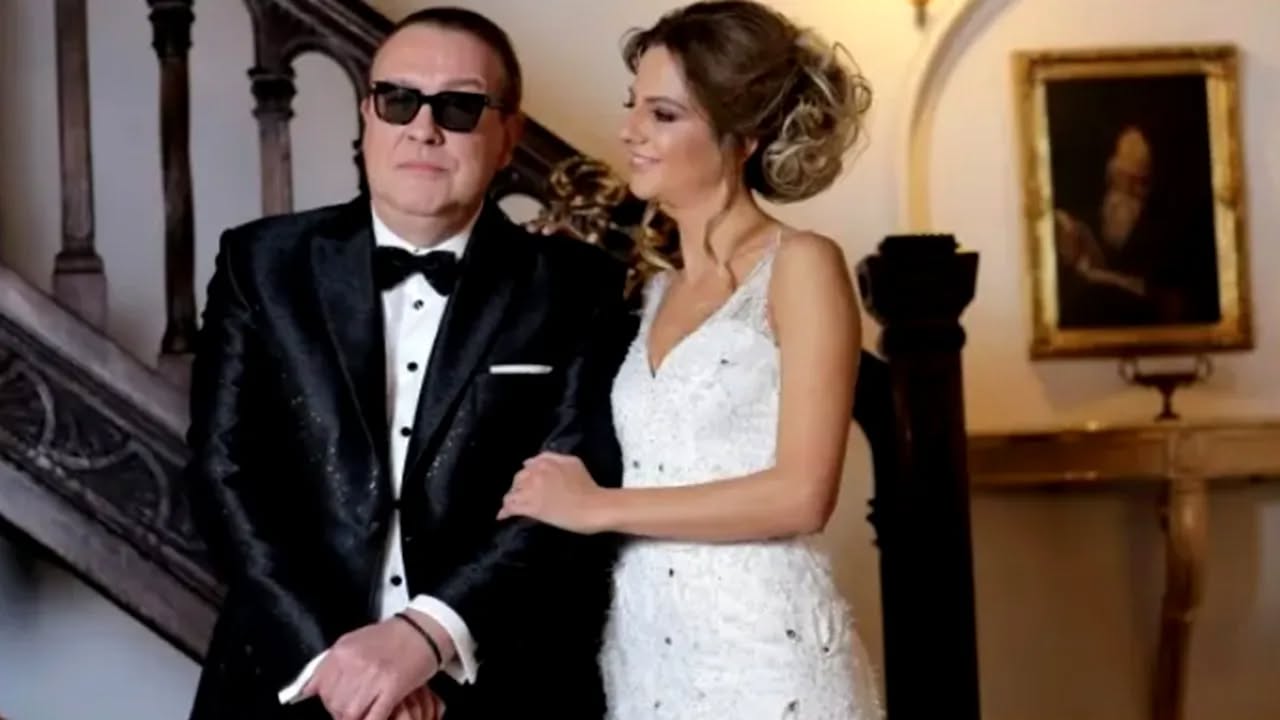 Gabriel Cotabiță și soția sa Alina, &icirc;n ziua nunții, &icirc;mbrăcați &icirc;n mire și mireasă, &icirc;n timp ce ea &icirc;l ținea de braț &icirc;n cadrul unei ședințe foto