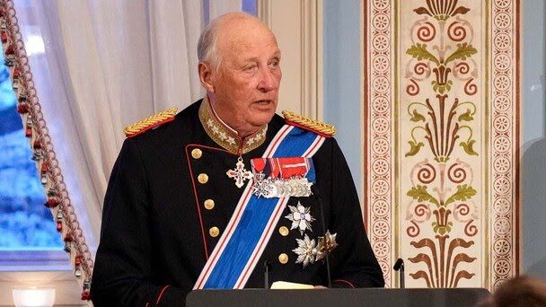 Regele Harald al V-lea al Norvegiei, la fereastră, st&acirc;nd la un pupitru și vorbind &icirc;n fața unei audiențe, l&acirc;ngă un perete cu o porțiune pictată