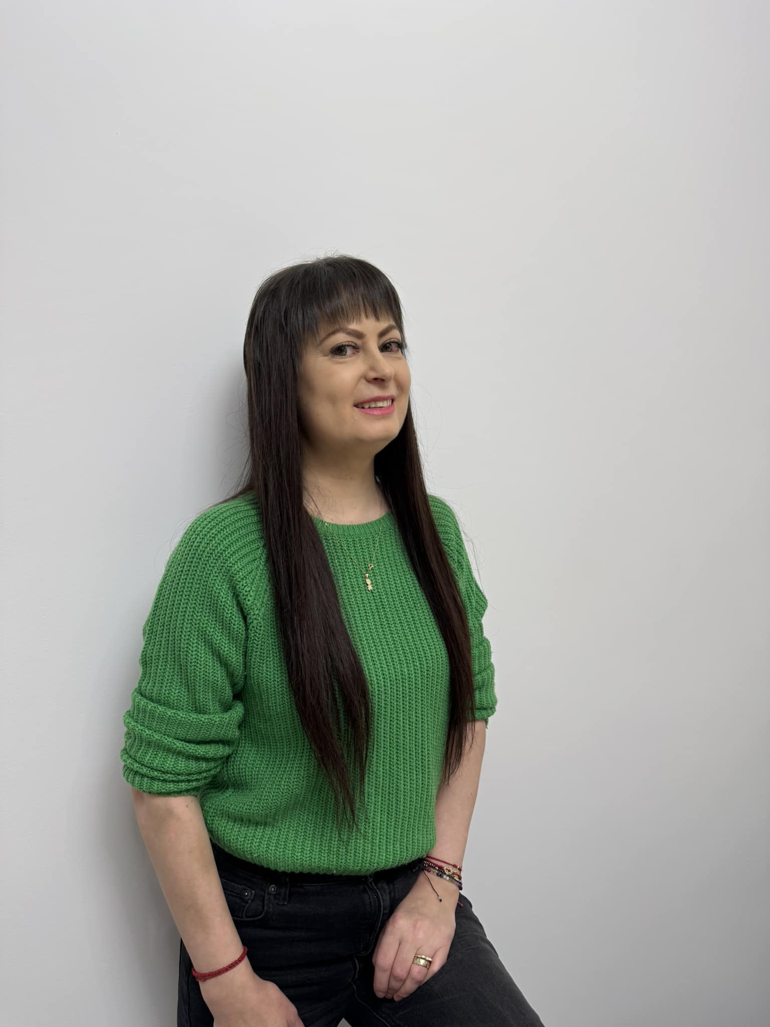 Daniela Pană, sprijinindu-se de un perete, &icirc;mbrăcată &icirc;n blugi negri și pulover verde, cu părul lung, brunet și cu breton