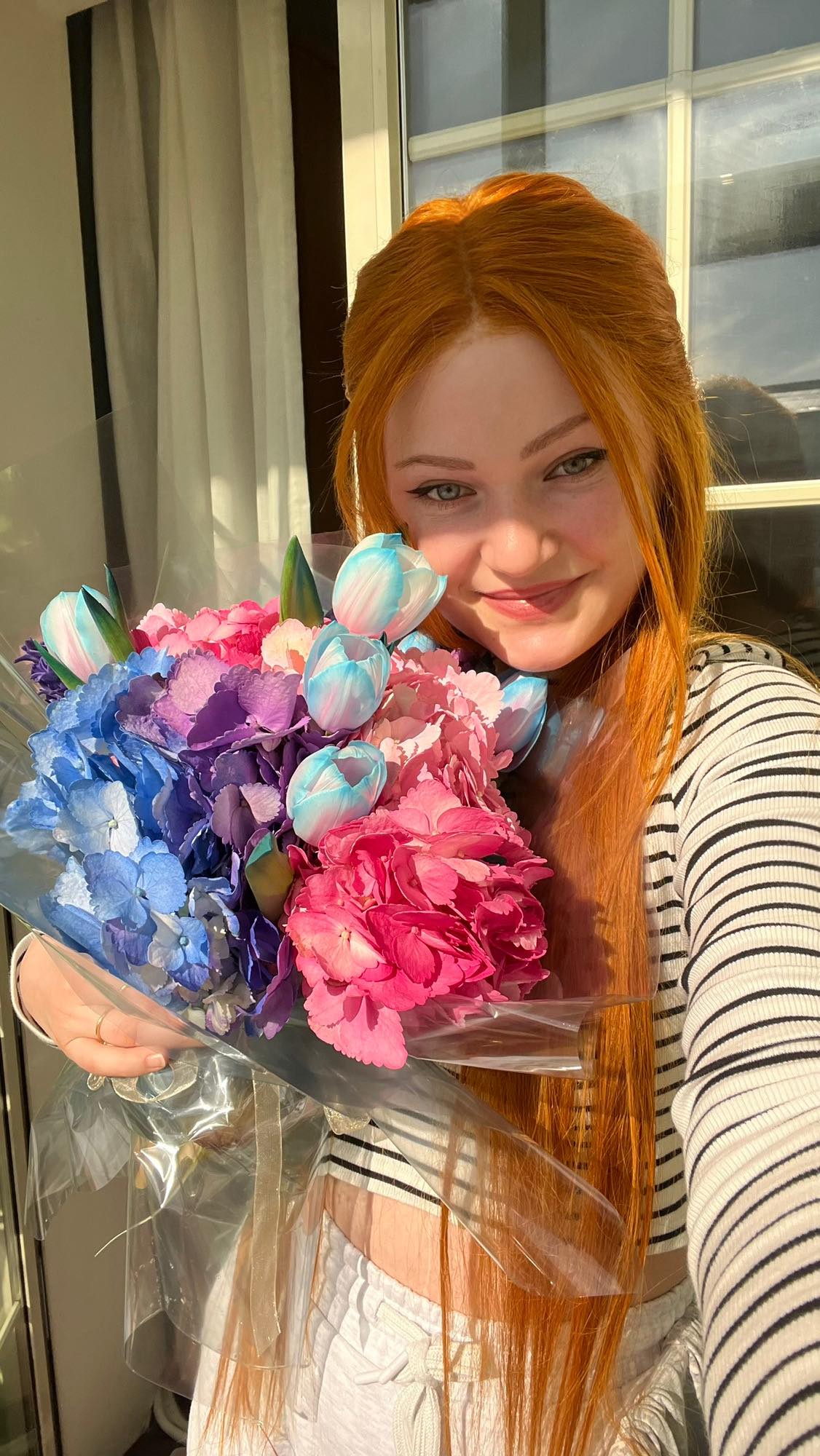 Andreea&nbsp;Anița z&acirc;mbitoare, cu un buchet de flori &icirc;n m&acirc;nă, purt&acirc;nd pe cap o perucă roșcată cu păr lung, &icirc;n timp ce &icirc;și făcea un selfie la soare