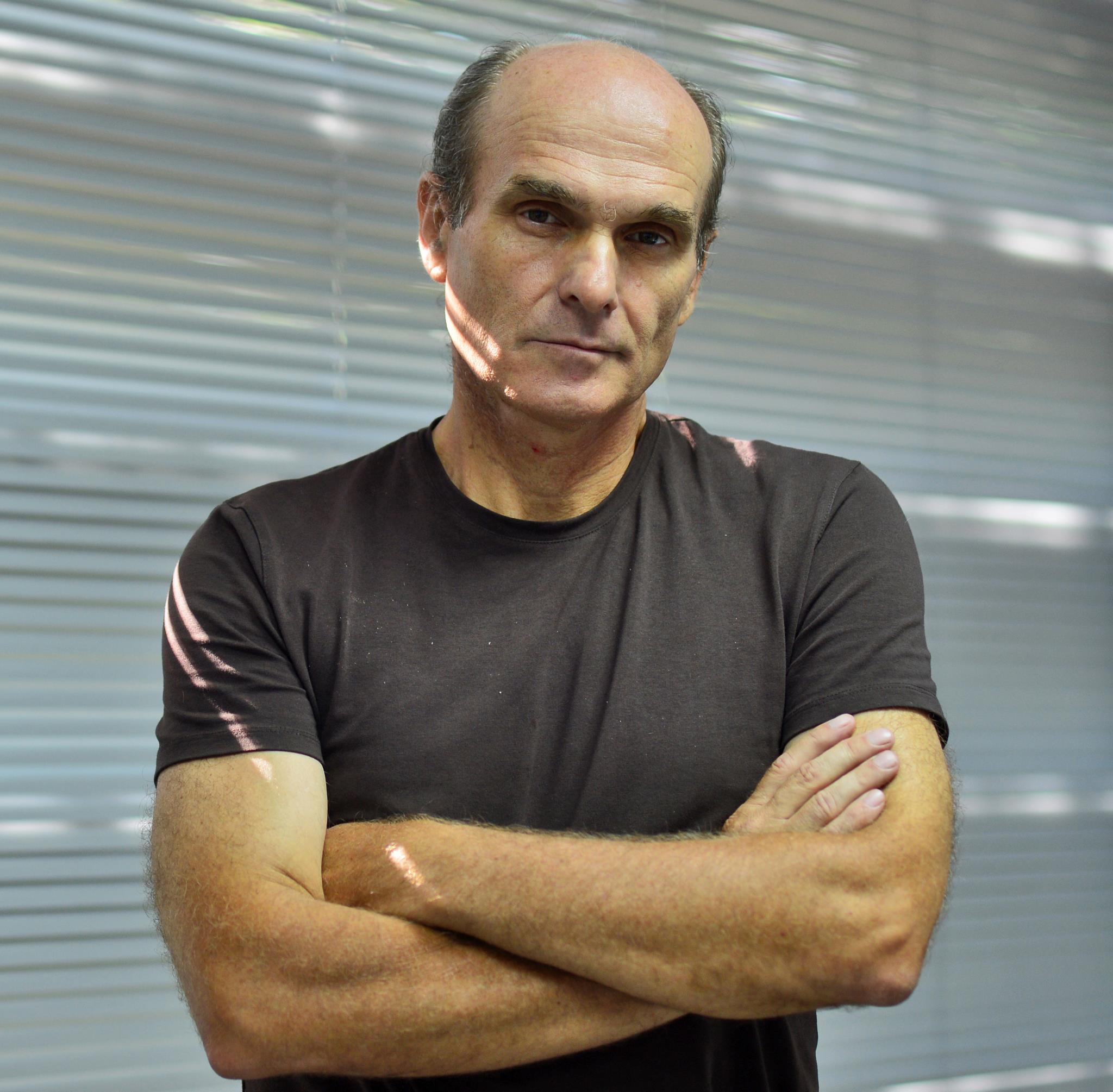 Cristian Tudor Popescu serios, st&acirc;nd cu m&acirc;inile &icirc;n s&acirc;n, &icirc;mbrăcat &icirc;ntr-un tricou gri &icirc;nchis