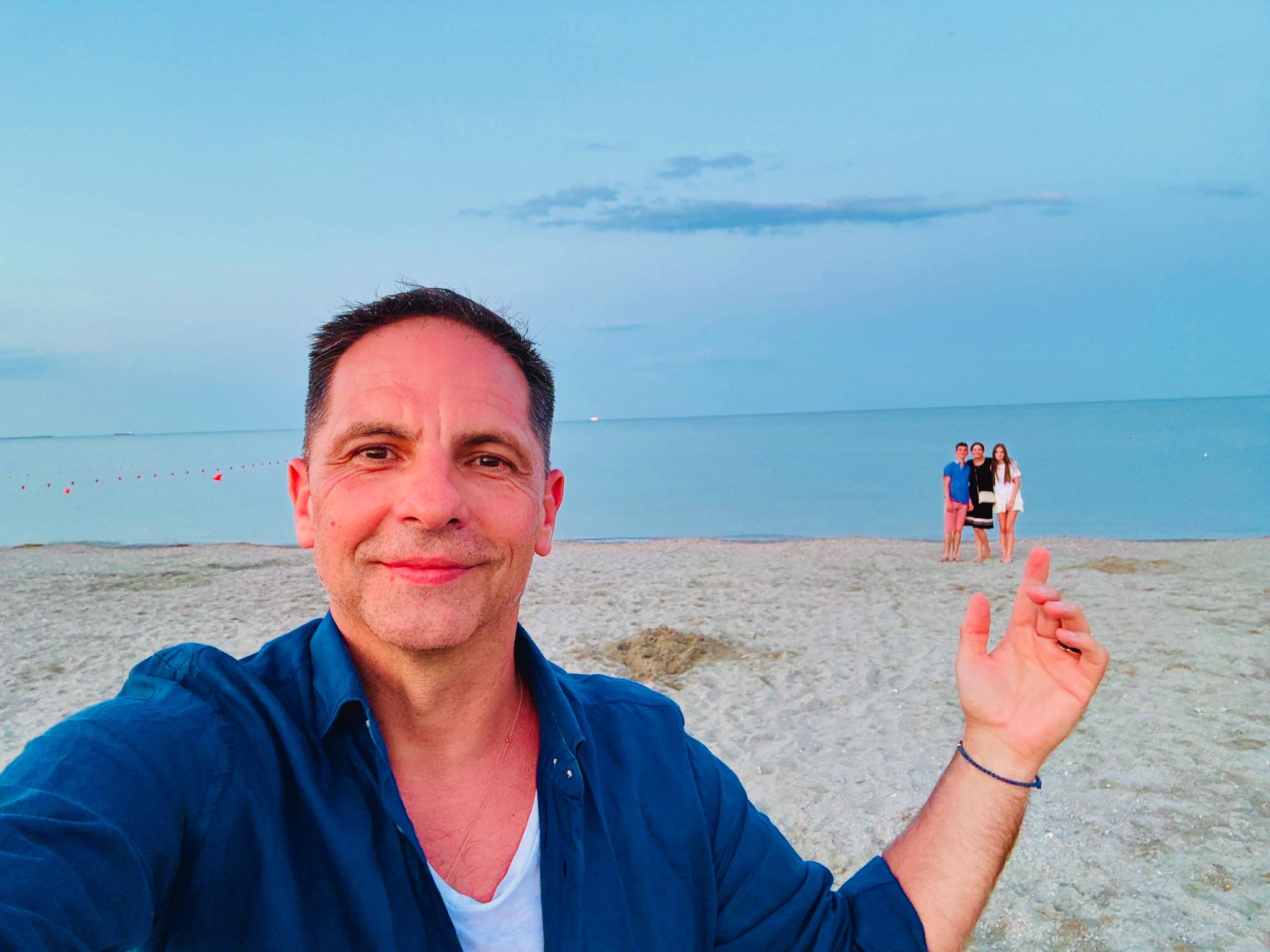 Dan Negru z&acirc;mbitor, pe plajă, alături de familia sa care stă mult mai departe de obiectivul camerei de fotografiat