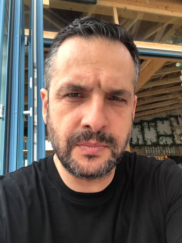 Mădălin Ionescu făc&acirc;ndu-și un selfie &icirc;n timp ce stă serios &icirc;n fața camerei foto, &icirc;n timp ce era &icirc;mbrăcat &icirc;ntr-un tricou negru