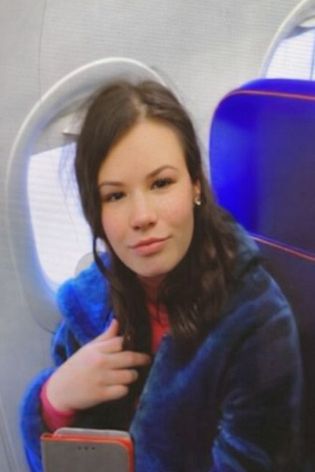 Elena Rebeca&nbsp;Burcioiu &icirc;n avion, &icirc;ntr-un hanorac albastru pufos, cu telefonul &icirc;n m&acirc;nă