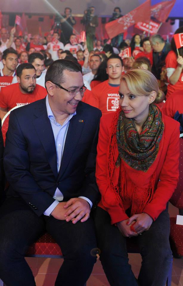 Victor Ponta și Daciana S&acirc;rbu st&acirc;nd pe scaune alăturate la o &icirc;nt&acirc;lnire cu alți membri ai partidului PSD, &icirc;mbrăcați &icirc;n tricouri cu emblema partidului