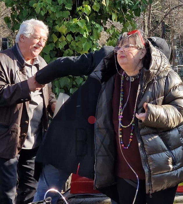 Anca Pandrea la cimitir, cu aparatul de oxigen după ea, &icirc;mbrăcată &icirc;n negru, cu geacă voluminoasă, purt&acirc;nd mărgle lungi la g&acirc;t